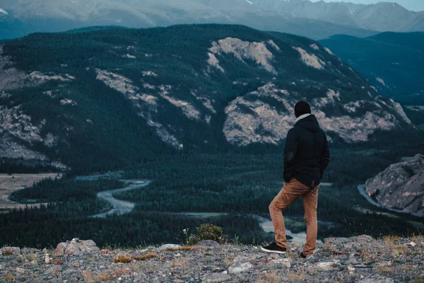 Hombre silueta permanecer en pico de roca afilada. Satisfacer excursionista disfrutar de la vista. Hombre alto en acantilado rocoso mirando hacia abajo al paisaje . — Foto de Stock