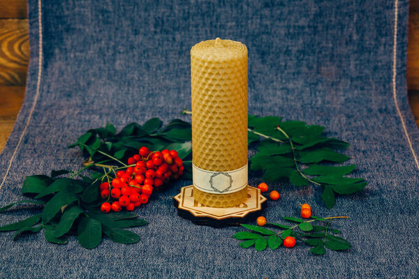 Christmas wax candle. Not burning candle, a mountain ash. A wooden background with fabric