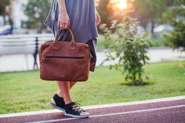 Sonbahar sokak moda bakmak. Genç esmer kızla bir gri örgü uzun elbiseli parkta elinde büyük parlak turuncu deri çanta