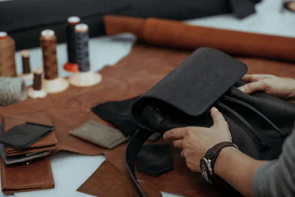 El maestro hace una bolsa de cuero. Un primer plano, un producto de la piel en las manos . — Foto de Stock