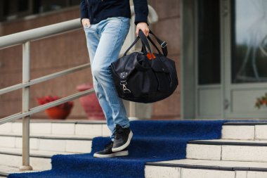 Genç adam bir çanta ile aşağı geliyor. Yakın çekim