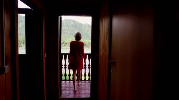 Το κορίτσι σε ένα κόκκινο φόρεμα έρχεται σε μπαλκόνι. — Αρχείο Βίντεο