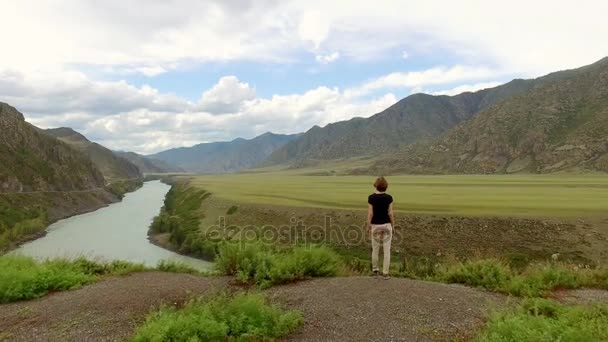 Het meisje geïnspireerd door een blik gaat naar de rivier. Mooie berg landschap — Stockvideo