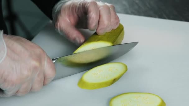 Close-up voedsel: chef-kok gehakte groene courgette op een witte tafel met mes — Stockvideo