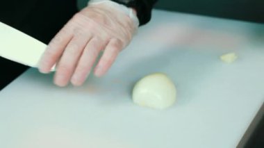 Bıçak kesim taze sebze ile el closeup. Genç Şef kesme soğan bir beyaz kesme pano portre üzerinde.