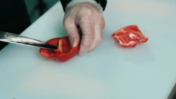 Mãos de Mans que cortam a pimenta vermelha do sino na placa de corte branca — Vídeo de Stock
