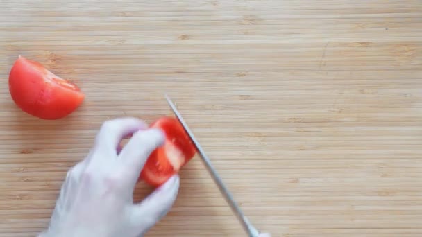 Von oben betrachtet schneidet ein Koch Tomaten auf einem Holzbrett mit einem Messer. die Hände wischen das Schneidebrett. — Stockvideo