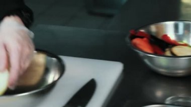 Şef taze sebze bir metal plaka diğerine kaydırır. Yukarı clouse.