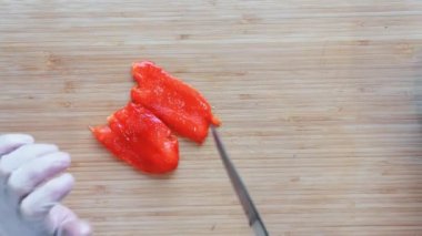 Ahşap kesme tahtası üzerinde kırmızı dolmalık biber Dilimleme bir şef kapatın. Üstten görünüm.