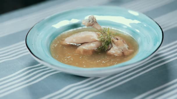 Clouse jedzenie. Restaurant. Gotowania. Zupa w niebieski płyta z kurcząt nogi, pierogi i zieleni. Szef kuchni włącza miskę zupy. — Wideo stockowe