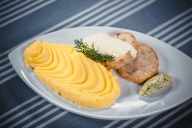 Kızarmış pirzola krema soslu patates püresi ile üst bakış beyaz tabakta. Plaka üzerinde mavi bir masa örtüsü beyaz şeritler ile tablo.