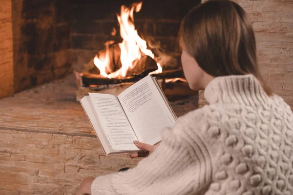 Cute girl sitting on floor by the fireplace — Stock Photo, Image