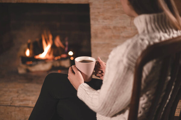 Girl in sweater sitting on chair and drinking tea