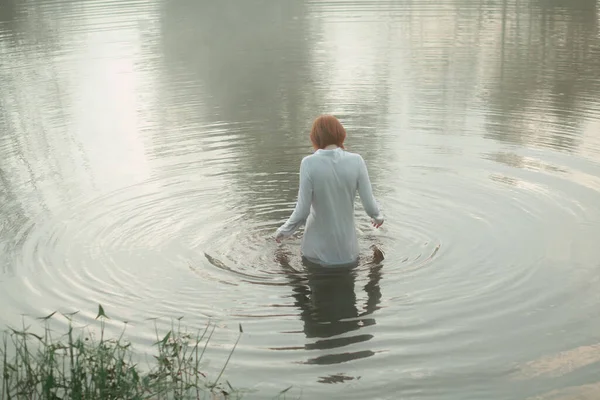 Belle femme aux cheveux roux debout dans un lac dans une forêt brumeuse — Photo