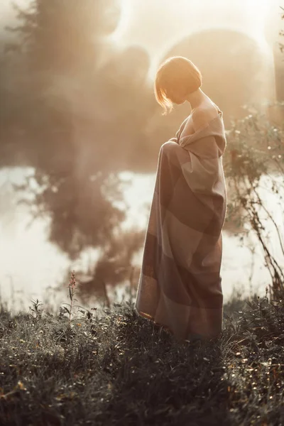 Flicka med kort hår stående i gräs täcker i filt — Stockfoto