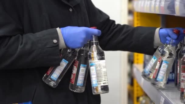 Närbild 4k videofilmer av många flaskor vodka på hyllorna i snabbköpet. Manlig hand tar en av flaskan. — Stockvideo