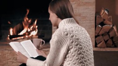 Kız evde oturup kitap okuyor.