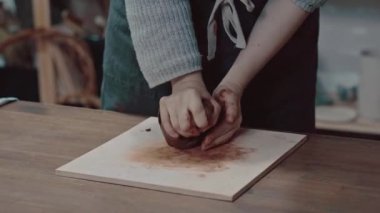 Kız ellerindeki çamuru eziyor. Çömlekçiler yakın plan çalışırlar. Kadın elleri kırışmış kil gibi yakın plan.