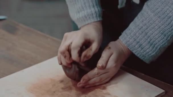 Flickan krossar leran i händerna. Potters jobbar på nära håll. Kvinnliga händer smulas sönder lera närbild. — Stockvideo
