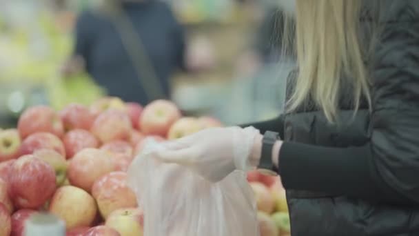 Vrouw in het gezicht beschermende masker in supermarkt supermarkt kiezen fruit appels. Quarantaineepidemie pandemie van covid-19 coronavirus — Stockvideo