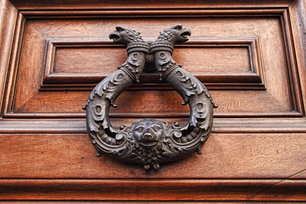 Old metal door handle knocker on wooden background. — Stock Photo, Image