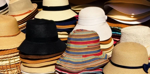 Una varietà di cappelli da donna estivi in un mercato di strada . — Foto Stock