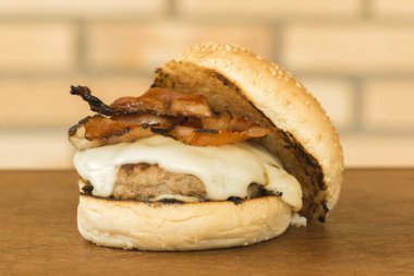 peynir, pastırma ve yan tarafa ahşap kesme tahtası ve tuğla arka plan üzerinde topuz ile ev yapımı hamburger