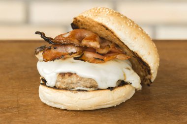 peynir ve ahşap kesme tahtası ve tuğla arka plan üzerinde pastırma ile ev yapımı hamburger