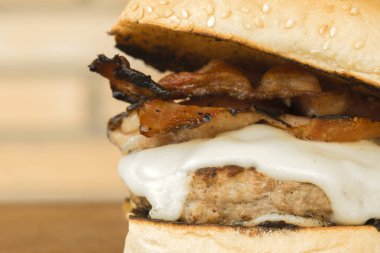 Ahşap kesme tahtası ve tuğla arka plan üzerinde peynir ve domuz pastırması ile ev yapımı hamburger üzerinde Kapat