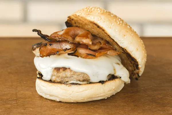 peynir ve ahşap kesme tahtası ve tuğla arka plan üzerinde pastırma ile ev yapımı hamburger