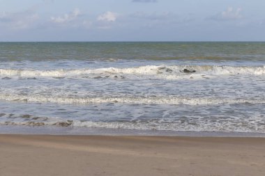 sakin dalgalar beyaz köpük mavi denizden plajın kumları bir sıcak yaz günü geliyor.