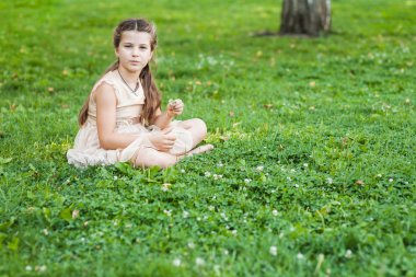 bir buket çiçek ile Çimenlikte oturan altın elbiseli kız