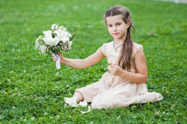 bir buket çiçek ile Çimenlikte oturan altın elbiseli kız