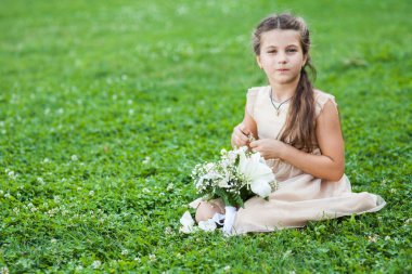 bir buket çiçek ile Çimenlikte oturan altın elbiseli kız