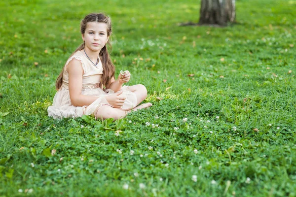 bir buket çiçek ile Çimenlikte oturan altın elbiseli kız
