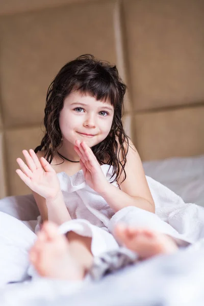 Fille lavée dans une serviette blanche assise sur un lit propre — Photo