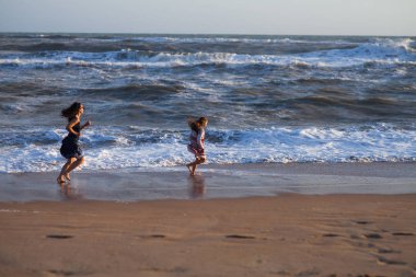 iki kız sörf hat boyunca kumlu plaj üzerinde çalıştırın.