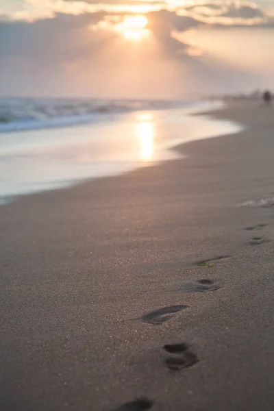 gün batımında kum plajındaki ayak izleri