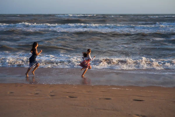 iki kız sörf hat boyunca kumlu plaj üzerinde çalıştırın.