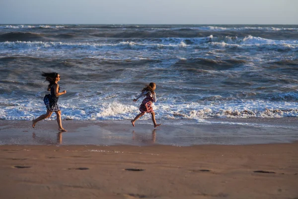 iki kız sörf hat boyunca kumlu plaj üzerinde çalıştırın.