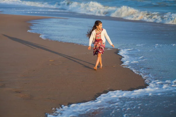 Dívka v sukni, stojí na břehu písečné a sledování na před bouřlivé moře — Stock fotografie