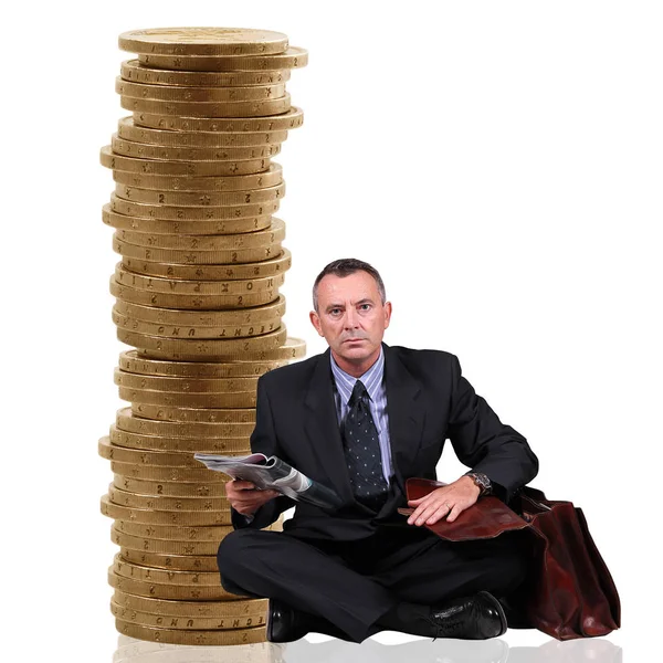 Человек, сидящий у стопки монет — стоковое фото