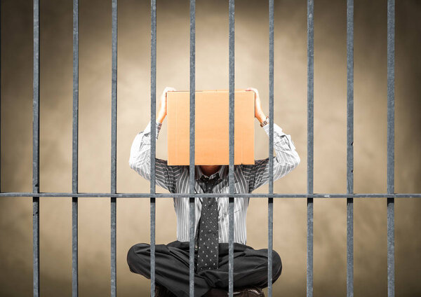 man sitting behind the bars of a prison
