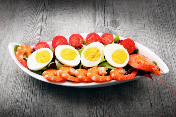 Salada com camarão, tomates e ovos em mesa de madeira — Fotografia de Stock