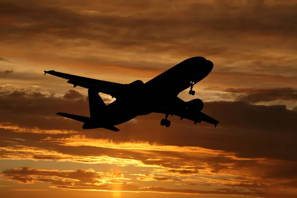 Avião voando ao pôr do sol — Fotografia de Stock