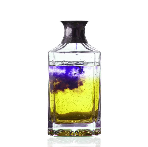 Botella con líquido amarillo y púrpura en fondo blanco — Foto de Stock