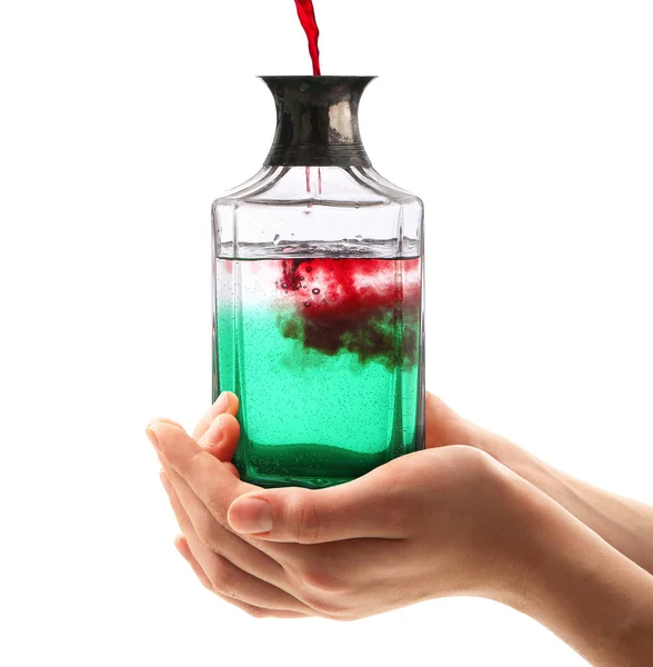 Bottiglia con liquido rosso e verde tenuta in mano su fondo bianco — Foto Stock