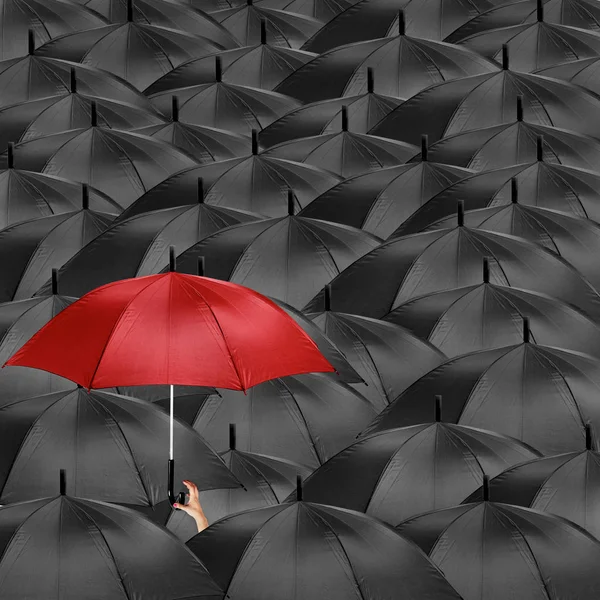 Guarda-chuva vermelho no meio de muitos guarda-chuvas pretos — Fotografia de Stock