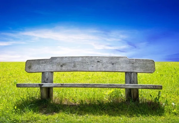 Banc en bois dans le champ vert — Photo