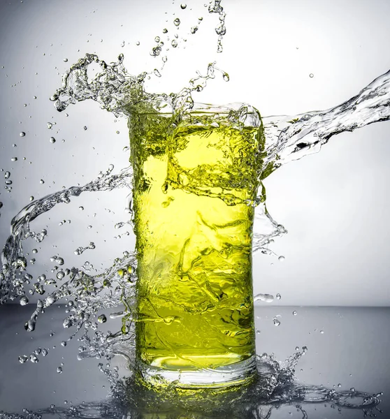 Glass with ice and liquid splash — Stock Photo, Image